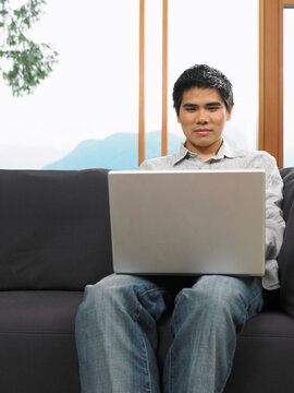Man Sitting on Sofa Using Laptop Computer