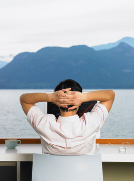Man Using Computer in Front of Window with Ocean View