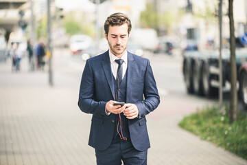 Businessman walking in the city using cell phone