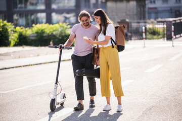 Young couple with electric scooter and smartphone on the street