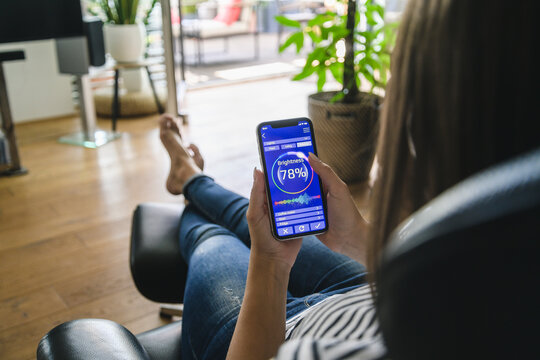 Young woman with smartphone with smart home control functions