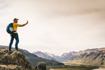Mature man taking selfie with smart phone while standing on rock against sky, Patagonia, Argentina