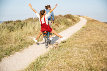 Carefree girlfriend enjoying bicycle ride with boyfriend on sunny day