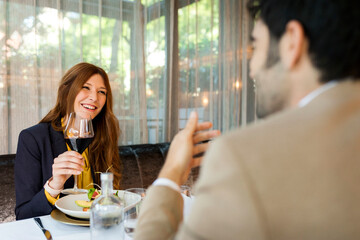 Smiling woman with glass of red wine looking at man in a restaurant