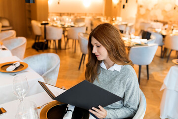Woman sitting at table in a restaurant reading menu