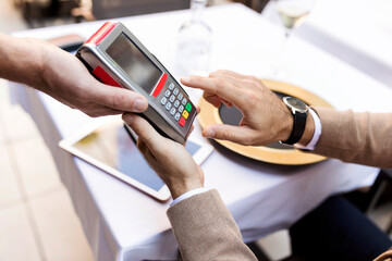 Man entering pin into card reader in a restaurant