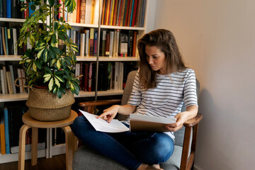Businesswoman reading document while sitting on chair in home office