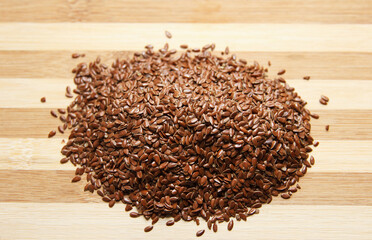 Many linen raw seeds lie on a wooden kitchen board. Raw baking ingredient. Top view.