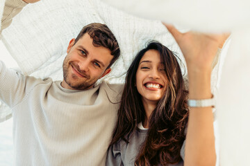 Young couple smiling while standing below shawl