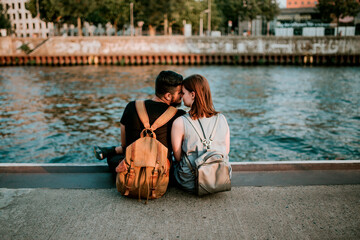 Affectionate young couple sitting at River Spree, Berlin, Germany