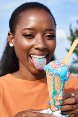Portrait of young woman with lightblue icecream sticking out tongue