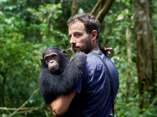 Cameroon, Pongo-Songo, Man carrying Chimpanzee (Pan troglodytes) in forest