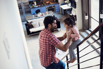 Father holding little daughter, sliding down railing