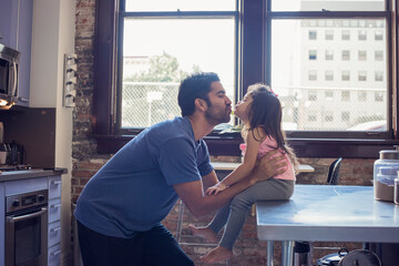 Father and daughter kissing in kitchen