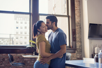 Young couple kissing in kitchen - obrazy, fototapety, plakaty