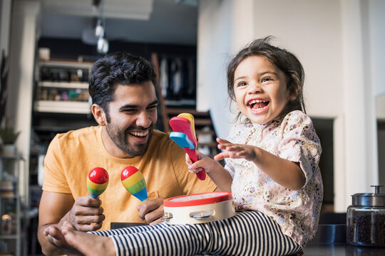 Father and daughter playing music in kitchen