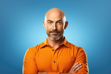 Obraz premium Handsome Bald Man Wearing a Orange Shirt on an Blue Background with Space for Copy 