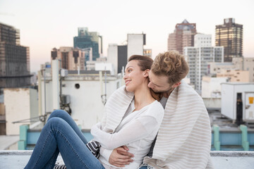 Romantic couple sitting on rooftop terrace, enjoying the view