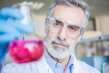 Scientist in lab holding beaker with liquid