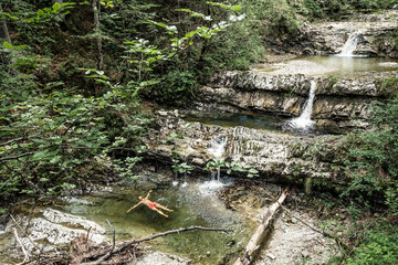 Germany, Upper Bavaria, Bavarian Prealps, lake Walchen, young man is swimming in a plunge pool
