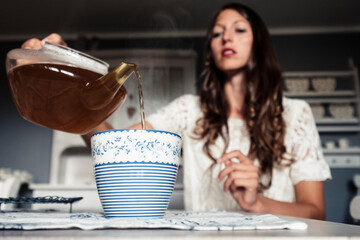 Young woman pouring tea into cup