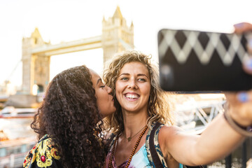 UK, London, two friends taking a selfie with Tower Bridge in background
