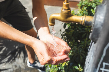Close up on hands and water spilling from a public fountain