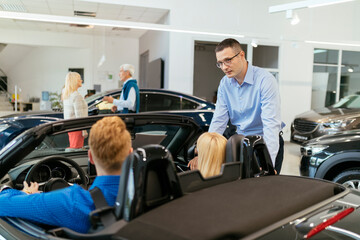 Fototapeta na wymiar Salesman advising customers in car dealership