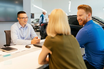 Salesperson advising couple in car dealership