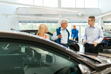 Salesman advising customers in car dealership