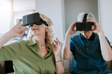 Senior couple at home sitting on couch wearing VR glasses