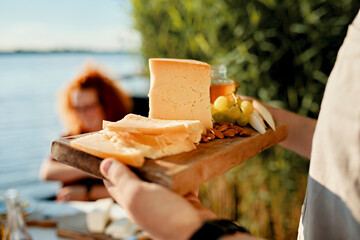 Man serving cheese platter for friends at a lake