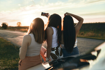 Female friends taking selfie while standing on road during sunset