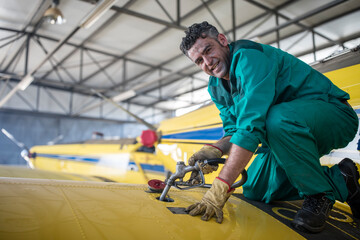 Mechanic in hangar refilling tank of light aircraft