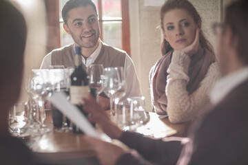Man and woman looking at man with wine bottle