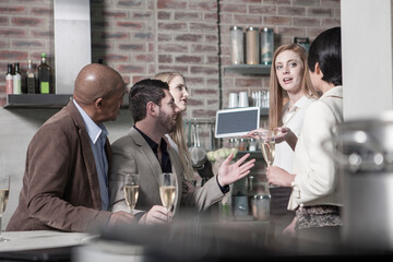 Friends with champagne glasses and tablet at home