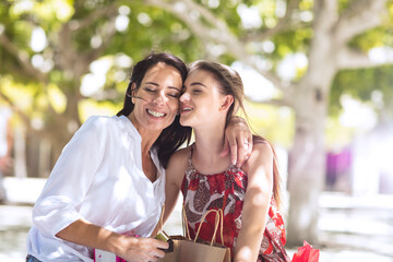 Happy mother and daughter with shopping bags embracing in the city