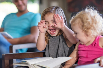 Two little girls reading book and having fun