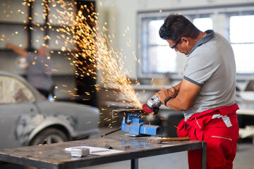 Mechanic using angle grinder in car workshop