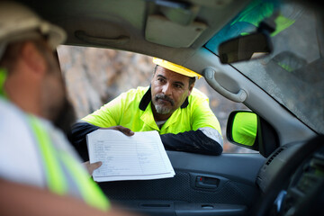 Worker handing over documents to colleague sitting in car