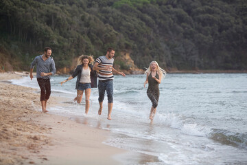 Four happy friends running at the beach