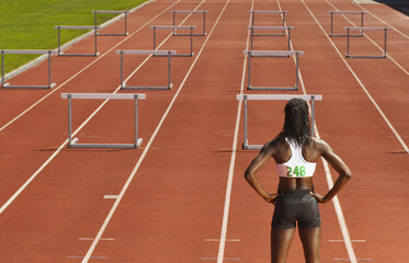 Back View of Woman Standing in Front of Hurdles on Track