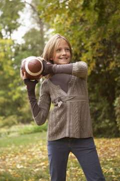Portrait of Girl Throwing American Football, in Autumn