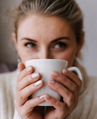 Woman holding a cup of coffee. Drink morning. A girl in a cozy house drinks a hot drink