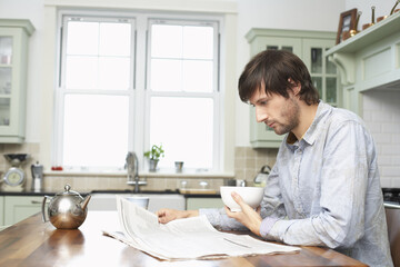 Man Reading Newspaper in Kitchen