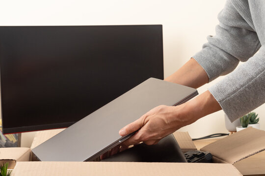 Female hands put old laptop computer in box with old used gadget devices for recycling. Planned obsolescence, e-waste, donation, electronic waste for reuse and recycle concept