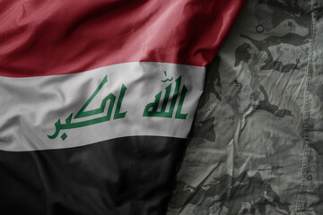 waving flag of iraq on the old khaki texture background. military concept.