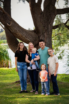 Outdoor family portrait in a city park by a lake on a warm fall afternoon and the youngest son has Down syndrome; Leduc, Alberta, Canada