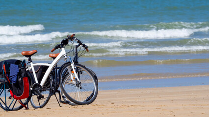 Fototapeta na wymiar Two bicycles loaded with luggage parked on the beach.