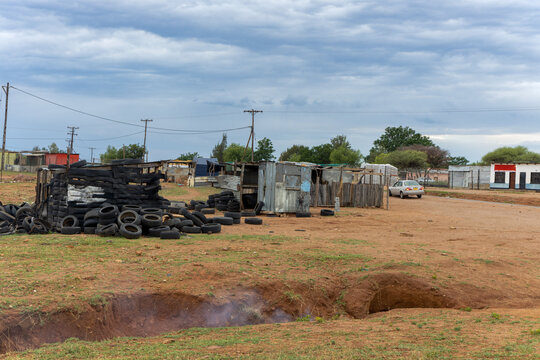 township informal settlement, shanty town made of corrugated iron sheets and tiers, smoking ditch in front